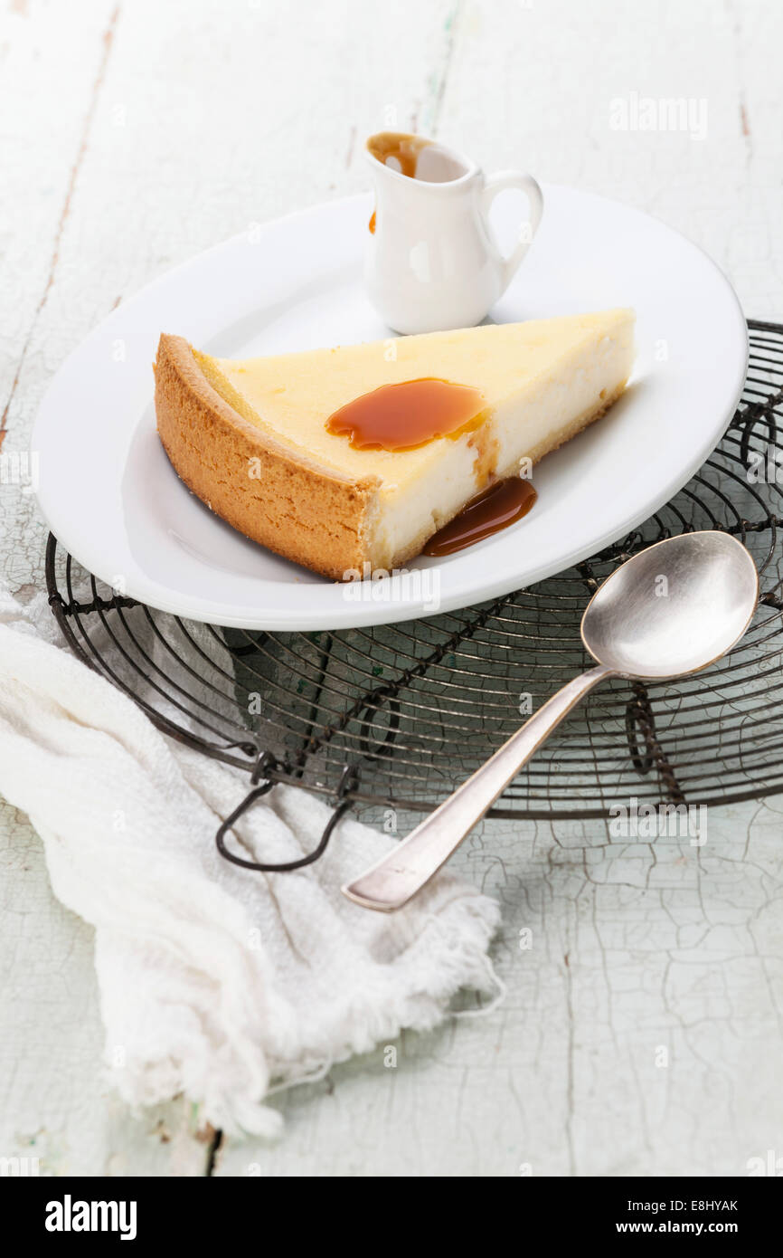 Cheesecake clásico y salsa de caramelo en la placa en la textura del fondo azul Foto de stock