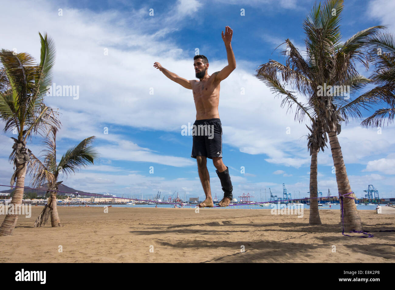 El hombre realizar volteretas y gimnasia desmonta en slackline atadas entre árboles de Plam Beach en España Foto de stock