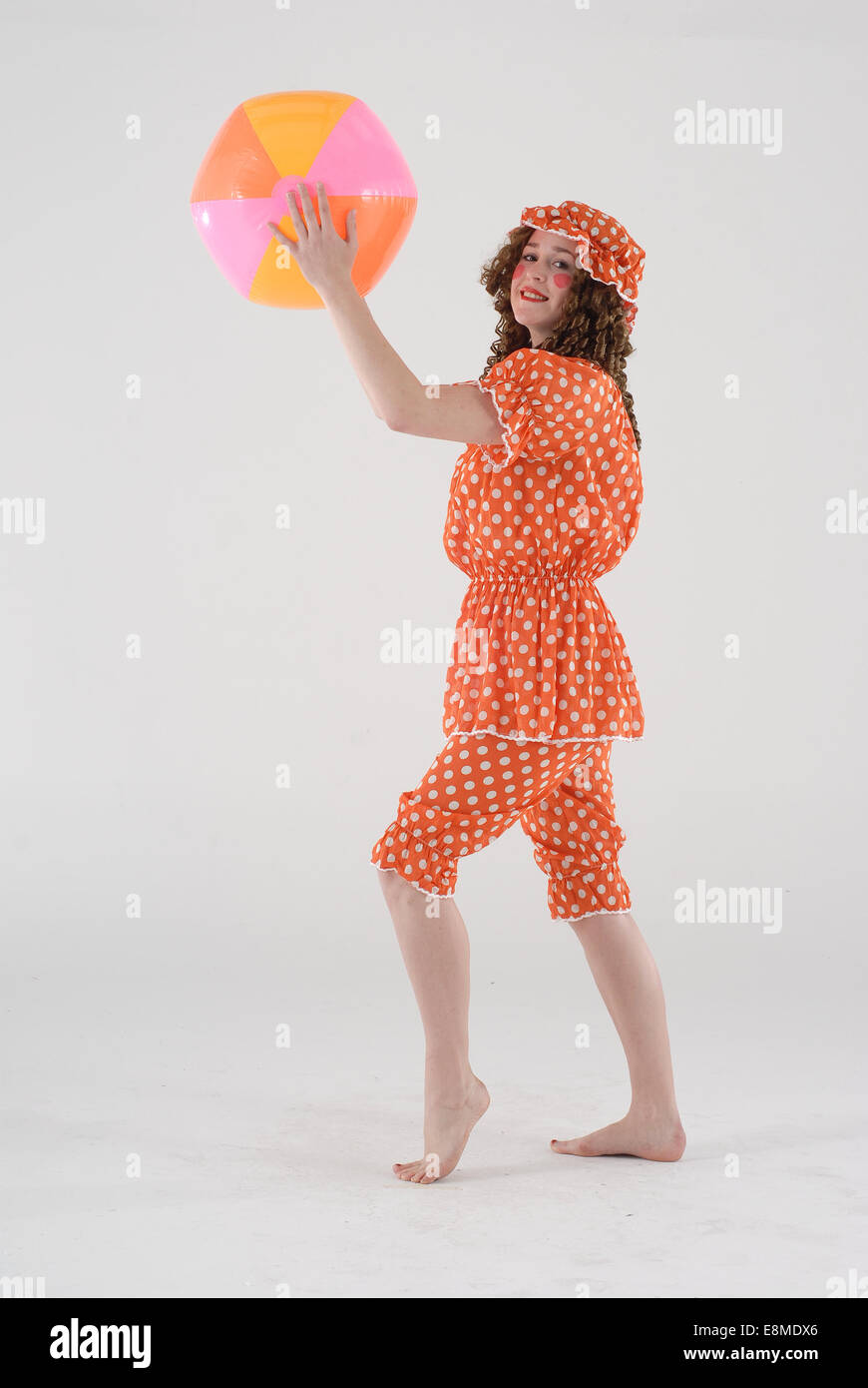 Mujer en vestidos de traje de comedia como un bañista victoriano en traje  de baño a la antigua usanza con pelota de playa Fotografía de stock - Alamy