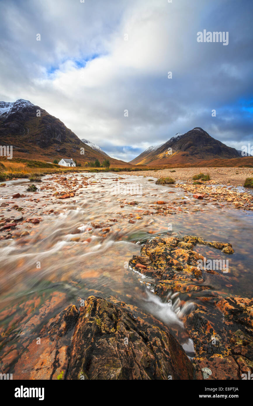 El Río Coupall en Glen Coe, Escocia con Lagangarbh Cottage en la distancia. Foto de stock