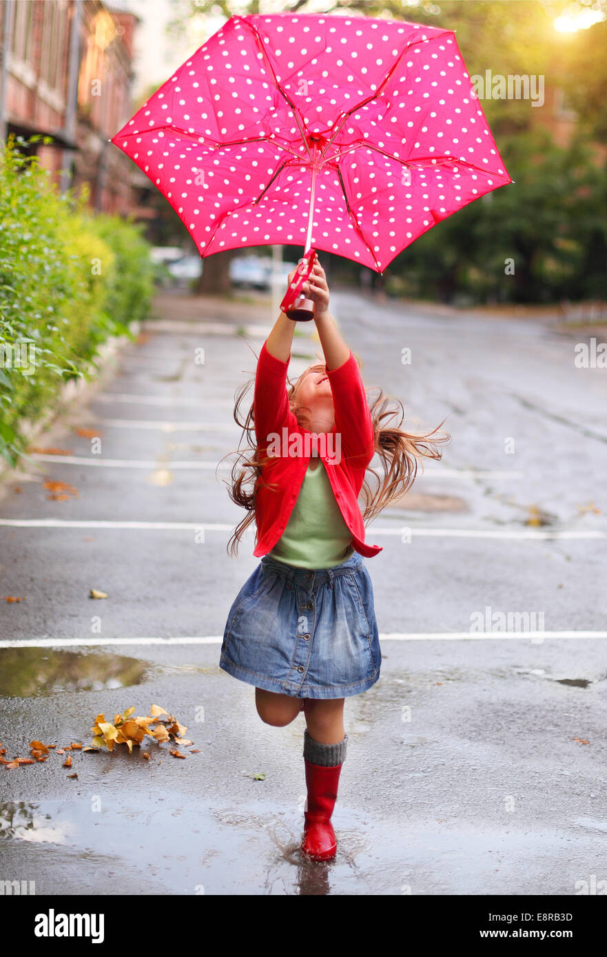 Niño con lunares paraguas vestidos de rojo botas de agua saltando en un  charco Fotografía de stock - Alamy