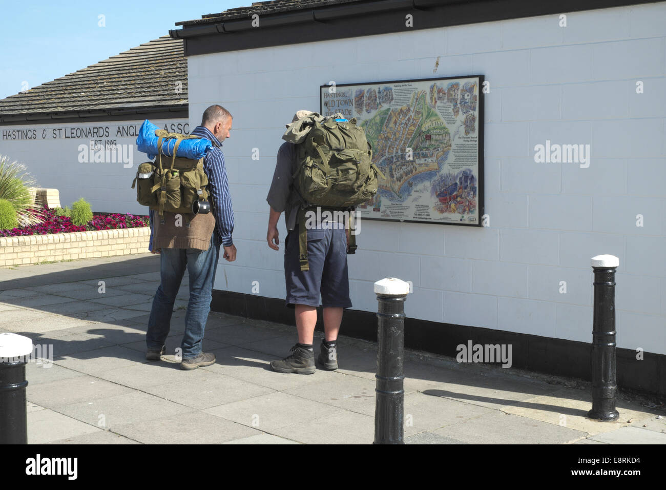 Mochileros mirando el mapa turístico en Hastings seafront East Sussex, Inglaterra Foto de stock