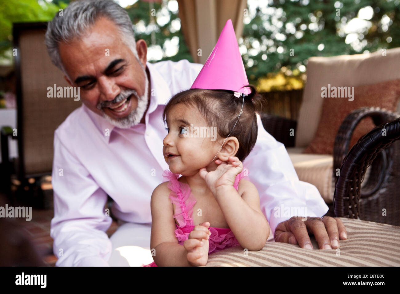 Abuelo sentado con su nieta en la fiesta de cumpleaños Foto de stock