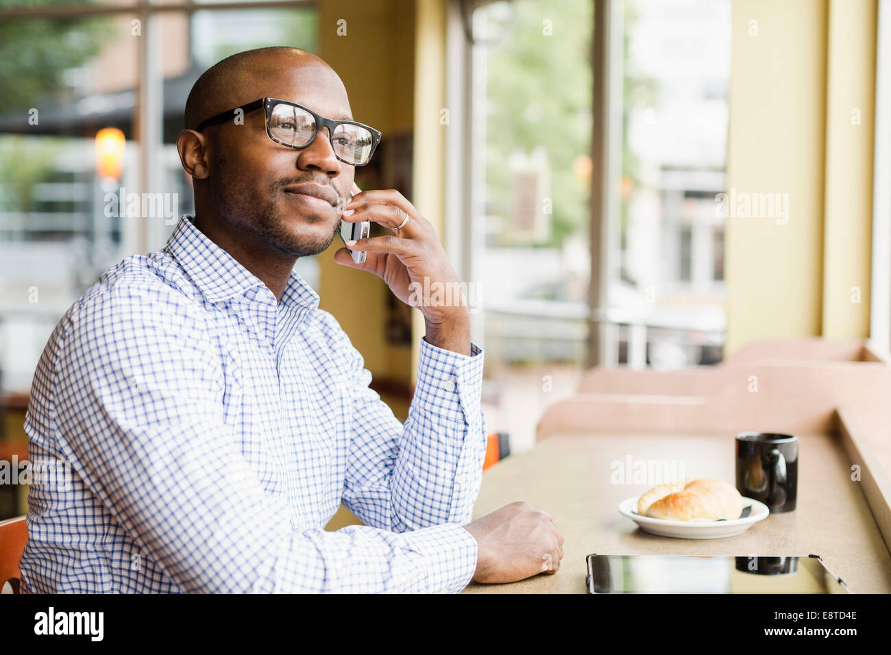Negro hombre hablando por teléfono celular en la cafetería. Foto de stock