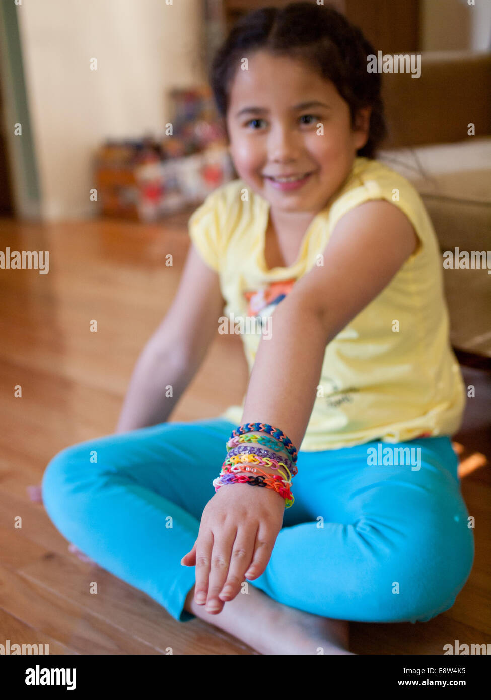 Una linda niña muestra su colorido Rainbow telar pulseras. Foto de stock