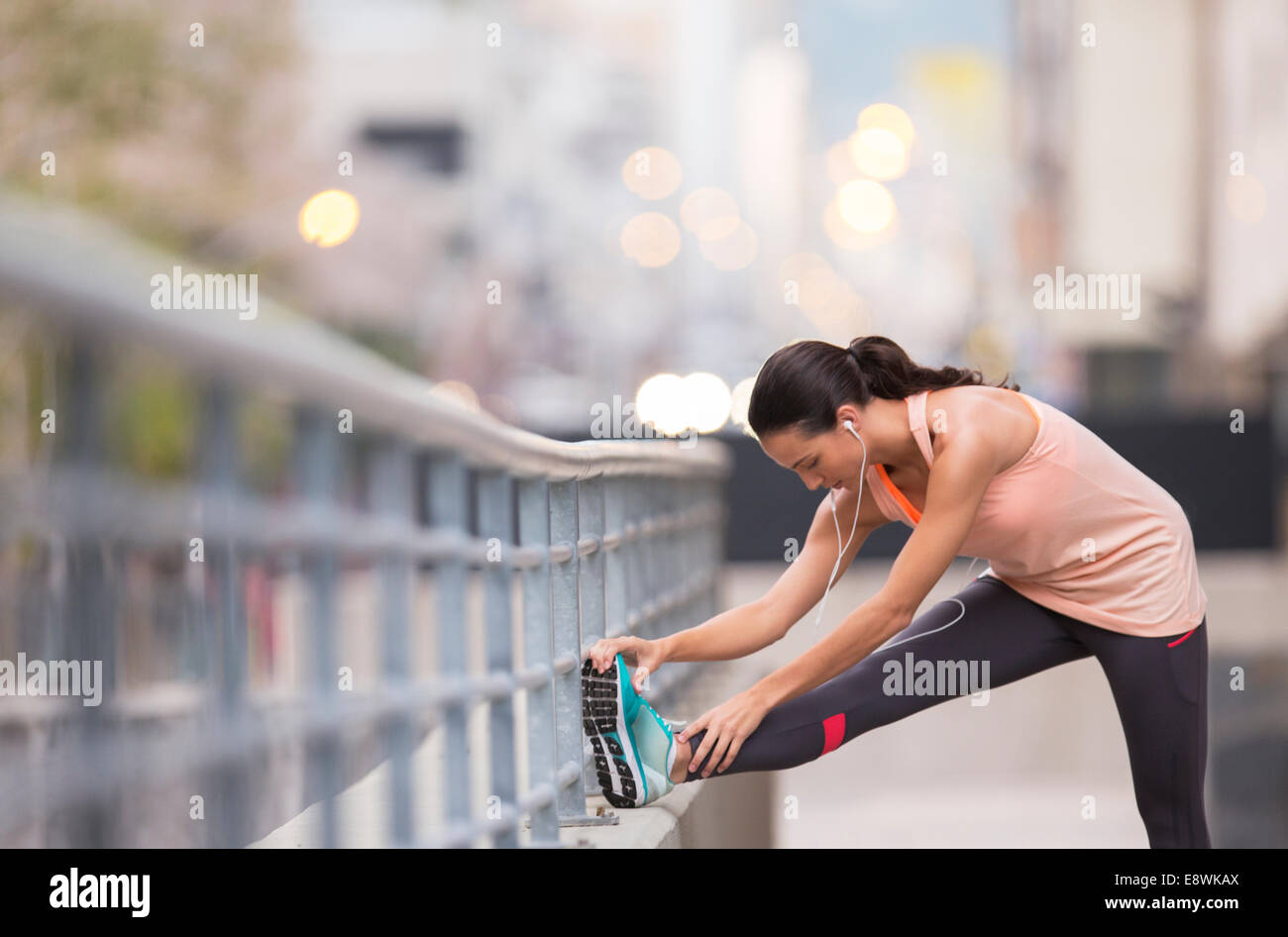 Mujer estiramientos antes de hacer ejercicio en las calles de la ciudad Foto de stock