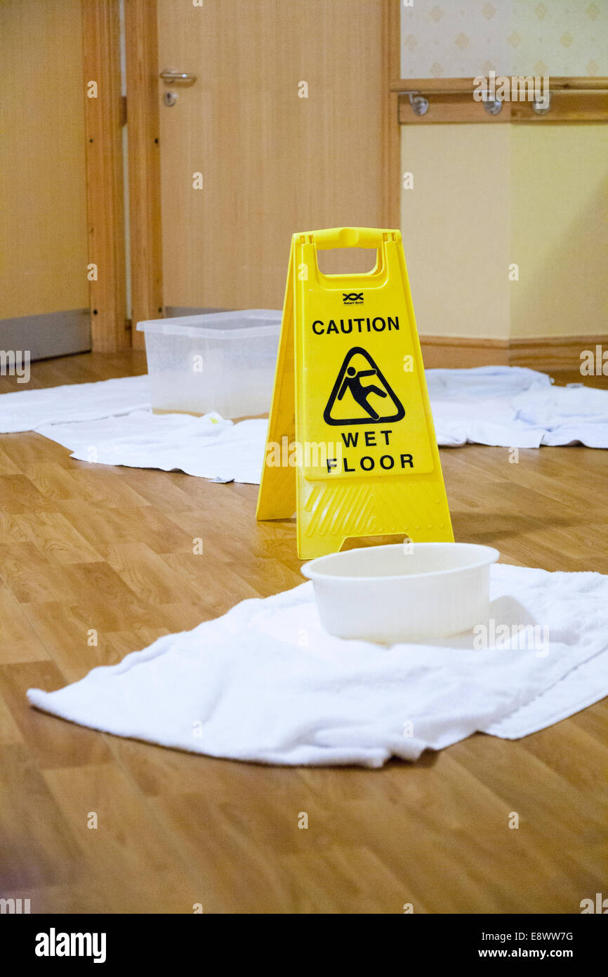 Colección cuencos y piso resbaloso / peligro de deslizamiento / piso mojado letrero donde filtraciones en el techo goteaba agua sobre un piso de hospital del NHS. UK Foto de stock