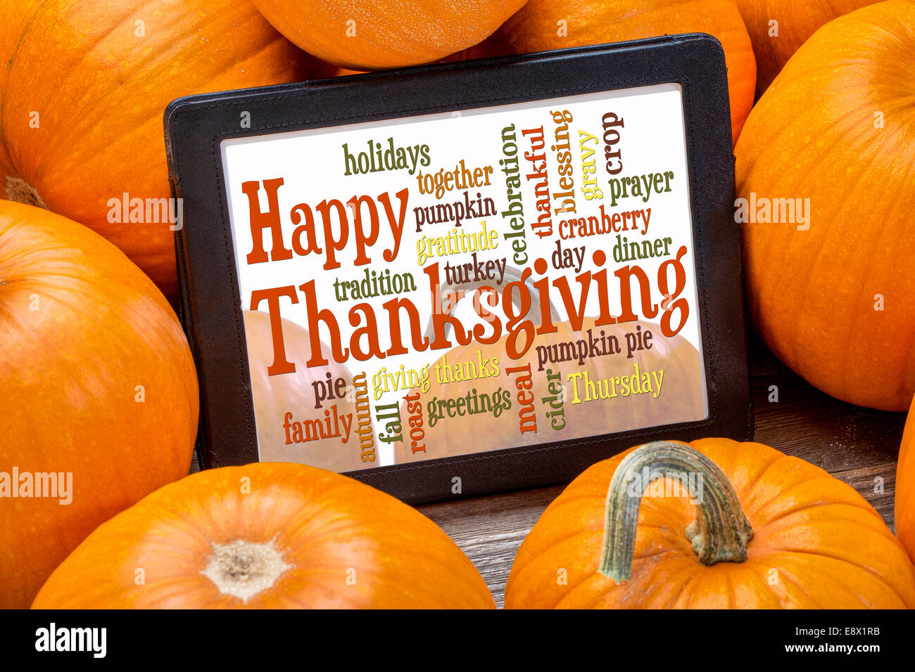 Feliz Día de Acción de Gracias palabra cloud en una tableta digital rodeado de calabazas Foto de stock
