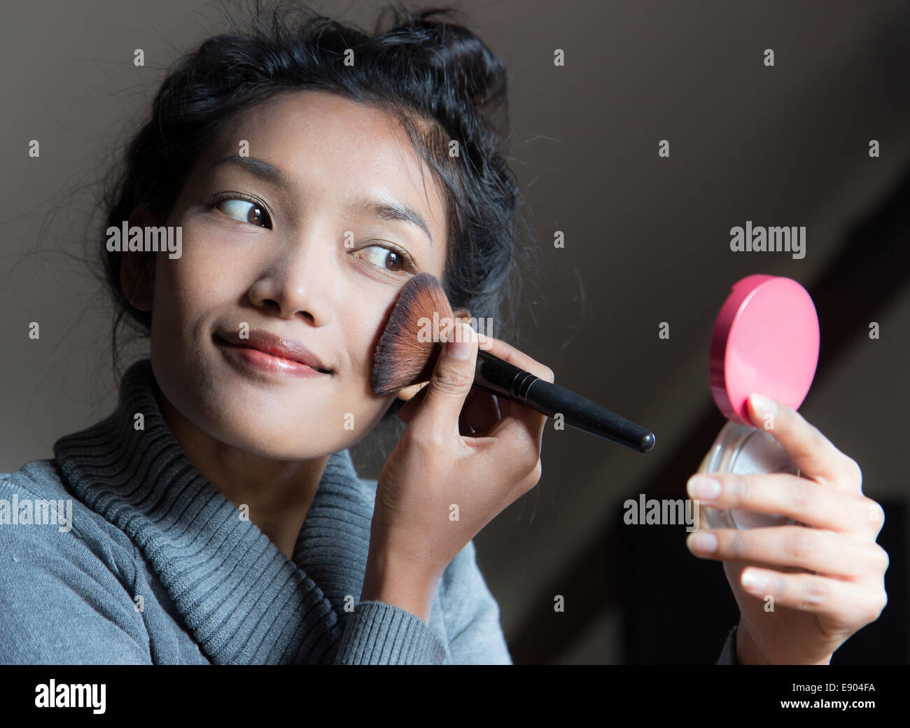 Mujer aplicar cosméticos seco en el rostro con el pincel de maquillaje Foto de stock