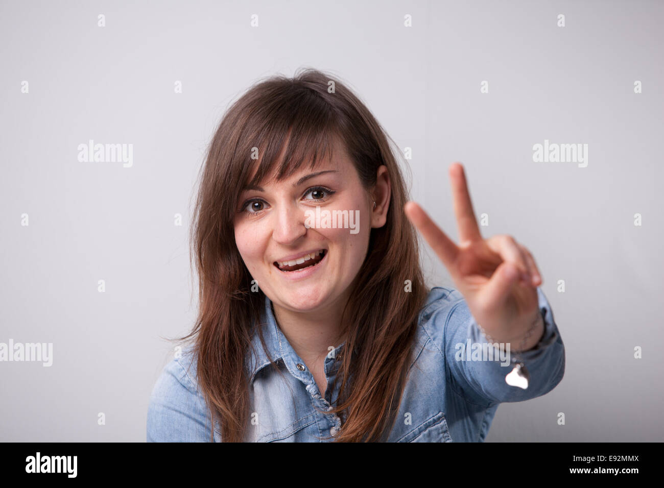 Éxito ordinaria chica mostrando los dedos de la victoria Foto de stock