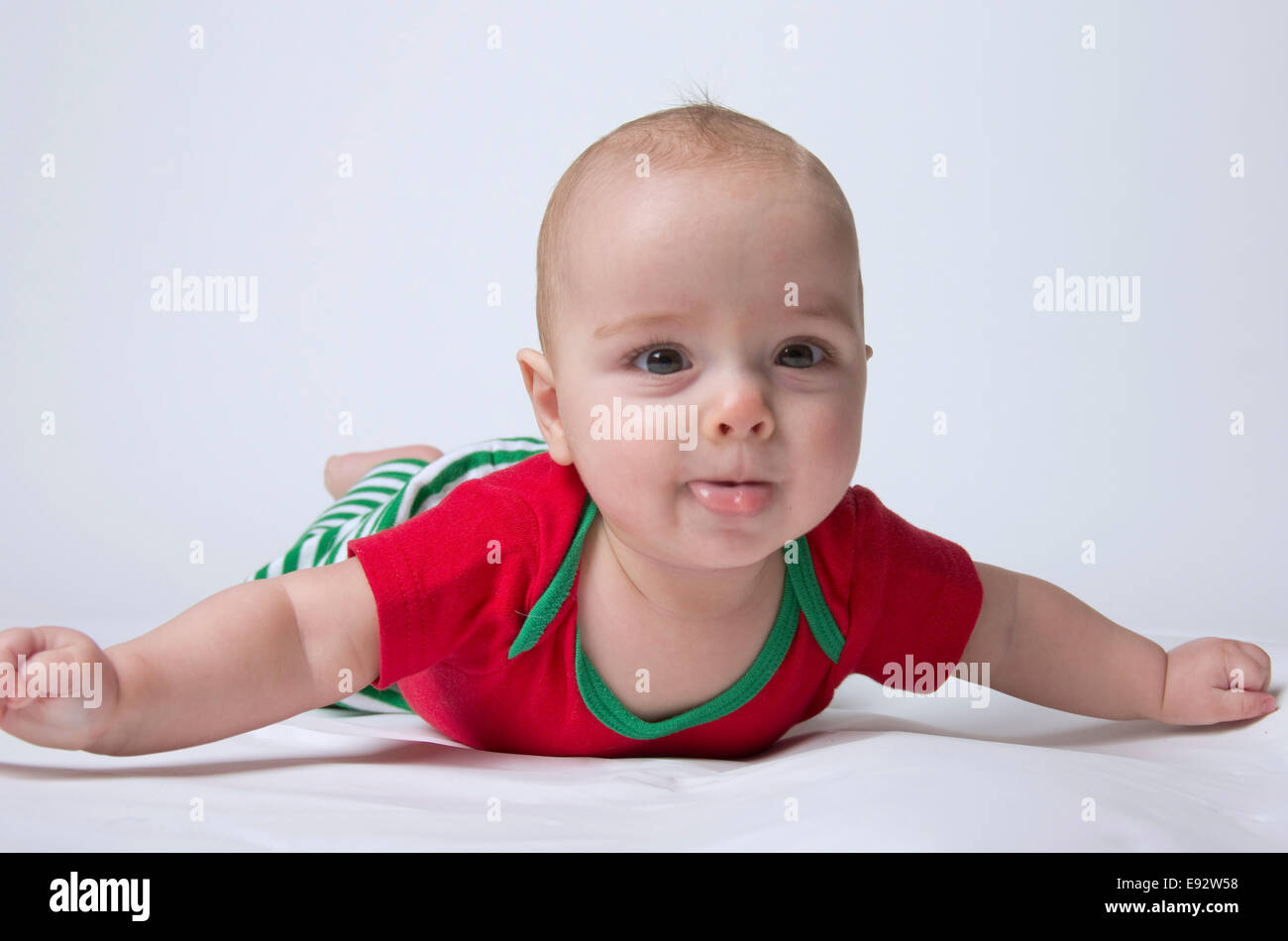 Adorable bebé de 9 meses niño sosteniendo la cabeza hacia arriba y la lengua fuera Foto de stock