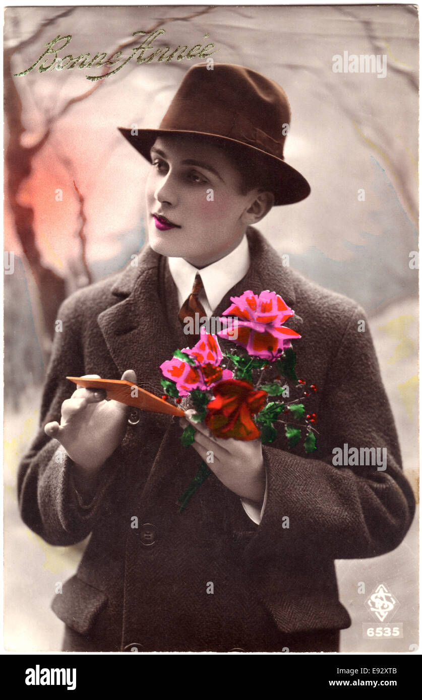 Mujer vestida de hombre", abrigo y el sombrero sosteniendo flores y tarjeta, "Bonne Francia", Hand-Colored postal francés, circa 1927 Foto de stock
