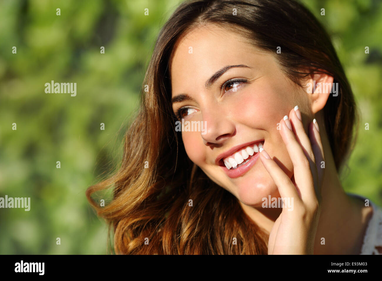 Mujer de belleza con una sonrisa perfecta y dientes blancos con un fondo verde Foto de stock