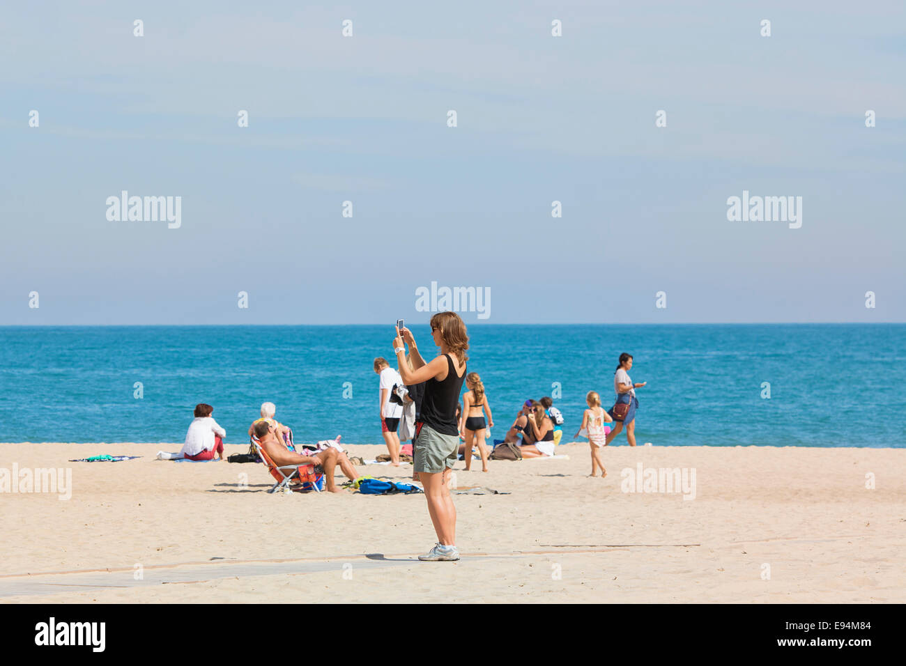 Mujer en la playa con teléfono móvil, toma de fotografías Foto de stock