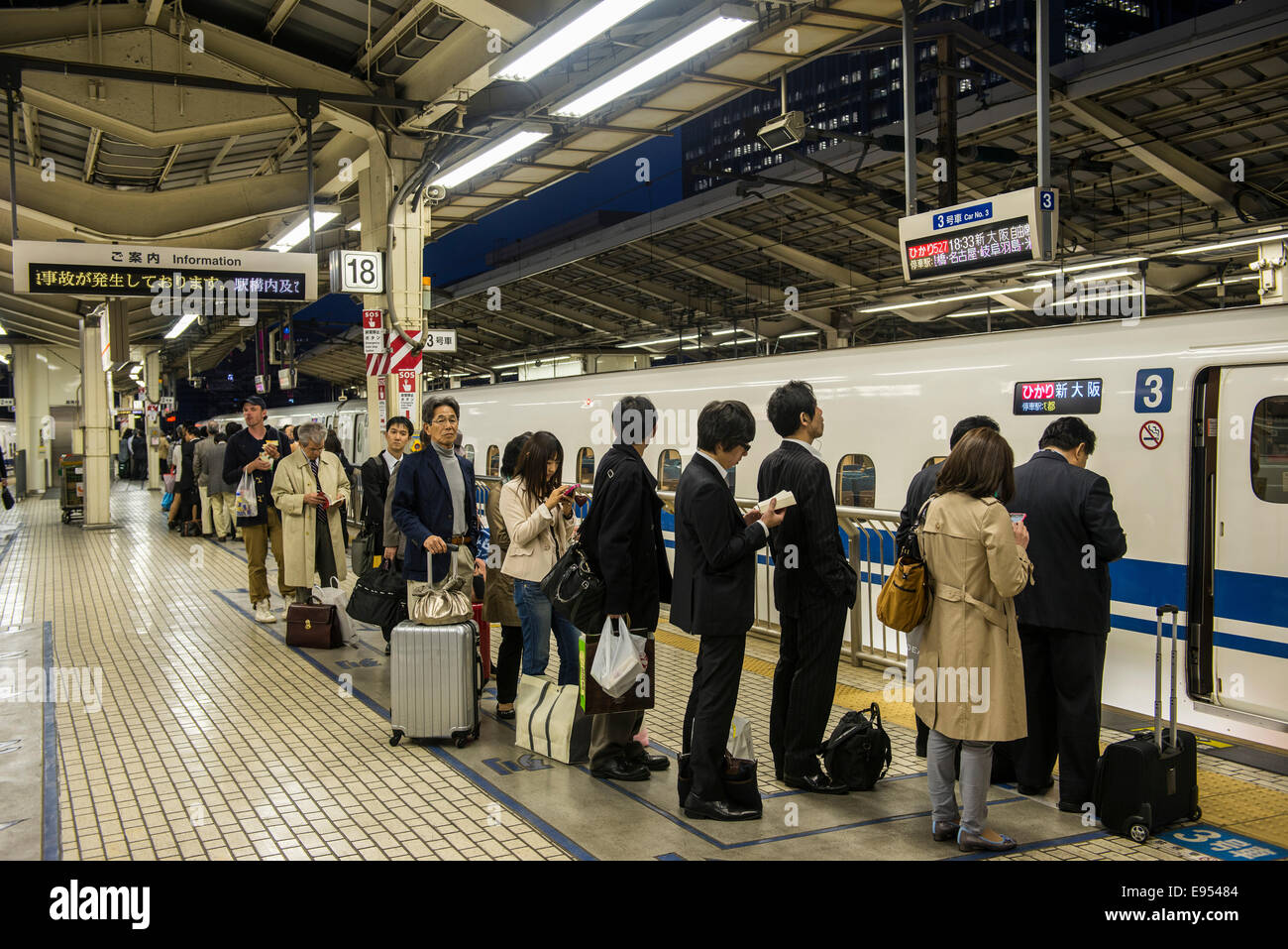 Los pasajeros esperando en línea, estación de tren shinkansen, Tokio, Japón Foto de stock