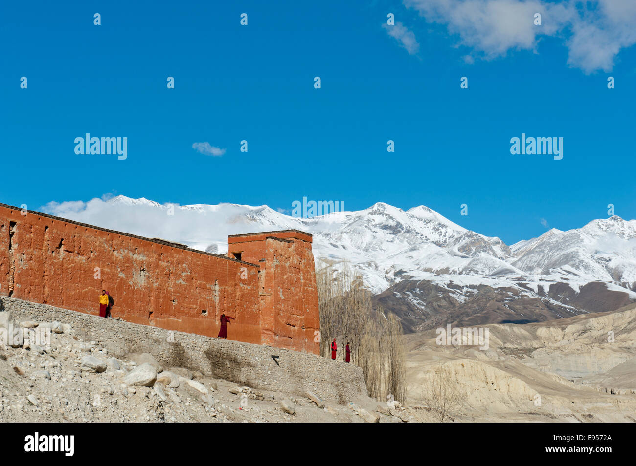 Pared de un edificio rojo con monjes, monasterio Gompa Chöde, montañas nevadas de Mustang Himal cordillera a volver Foto de stock