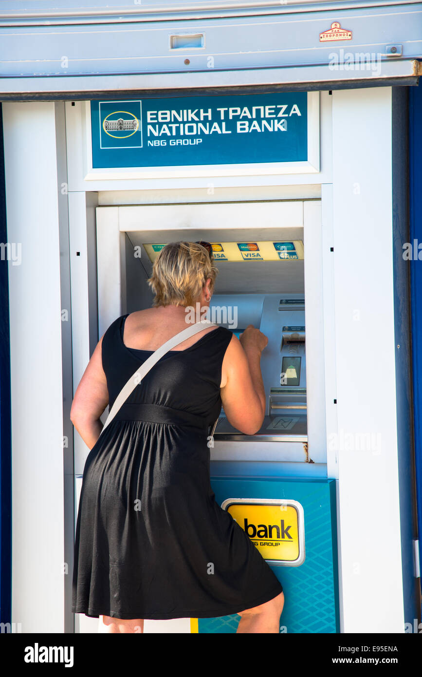 Recibiendo dinero de bankmachine turístico fuera de banco en Grecia Foto de stock