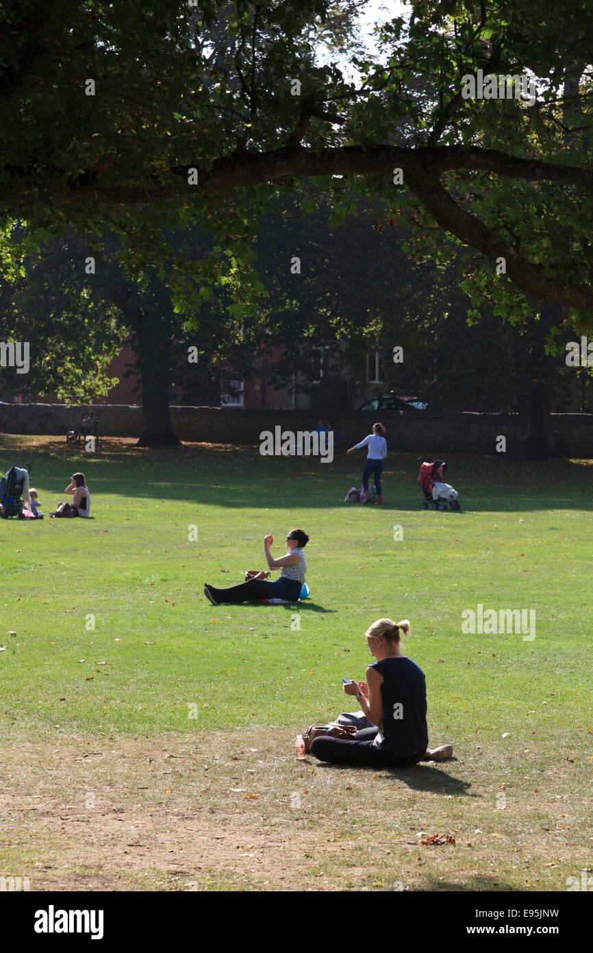 Gente sentada en el césped, disfrutando del sol de verano Foto de stock