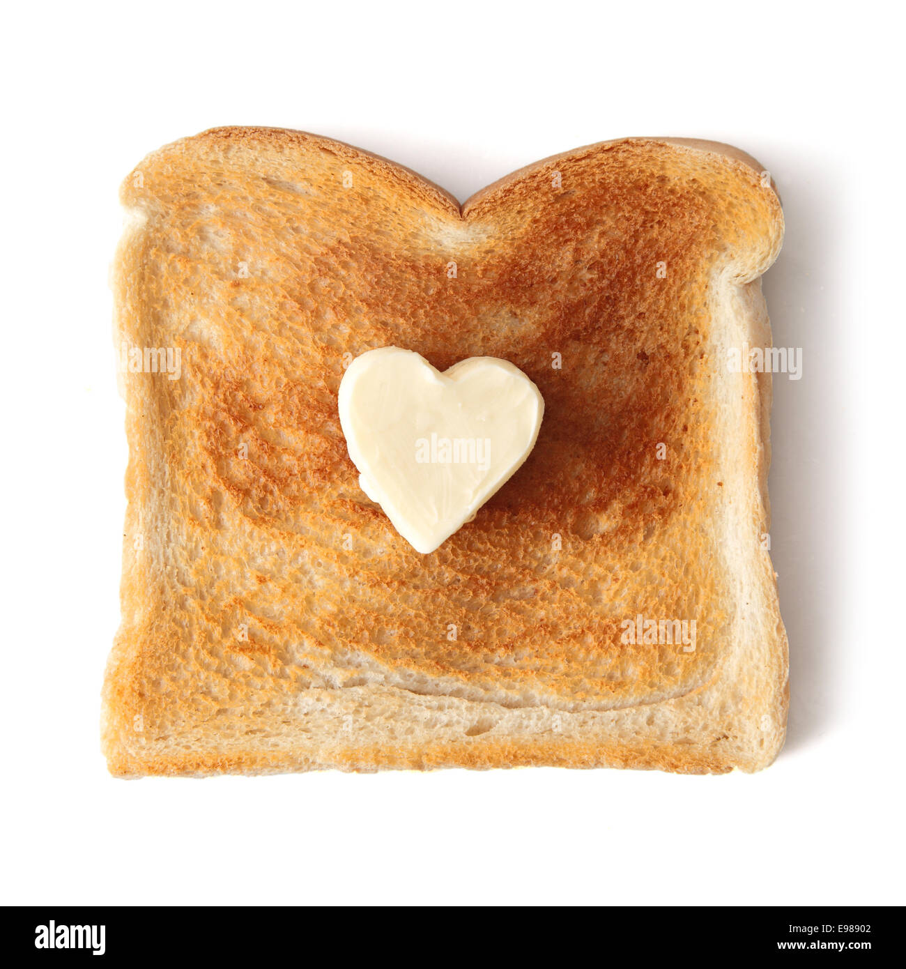 Rebanada de pan blanco tostado sobre un fondo blanco. Una mantequilla pat en la forma de un corazón de amor se ha colocado en el centro de la tostada. Foto de stock