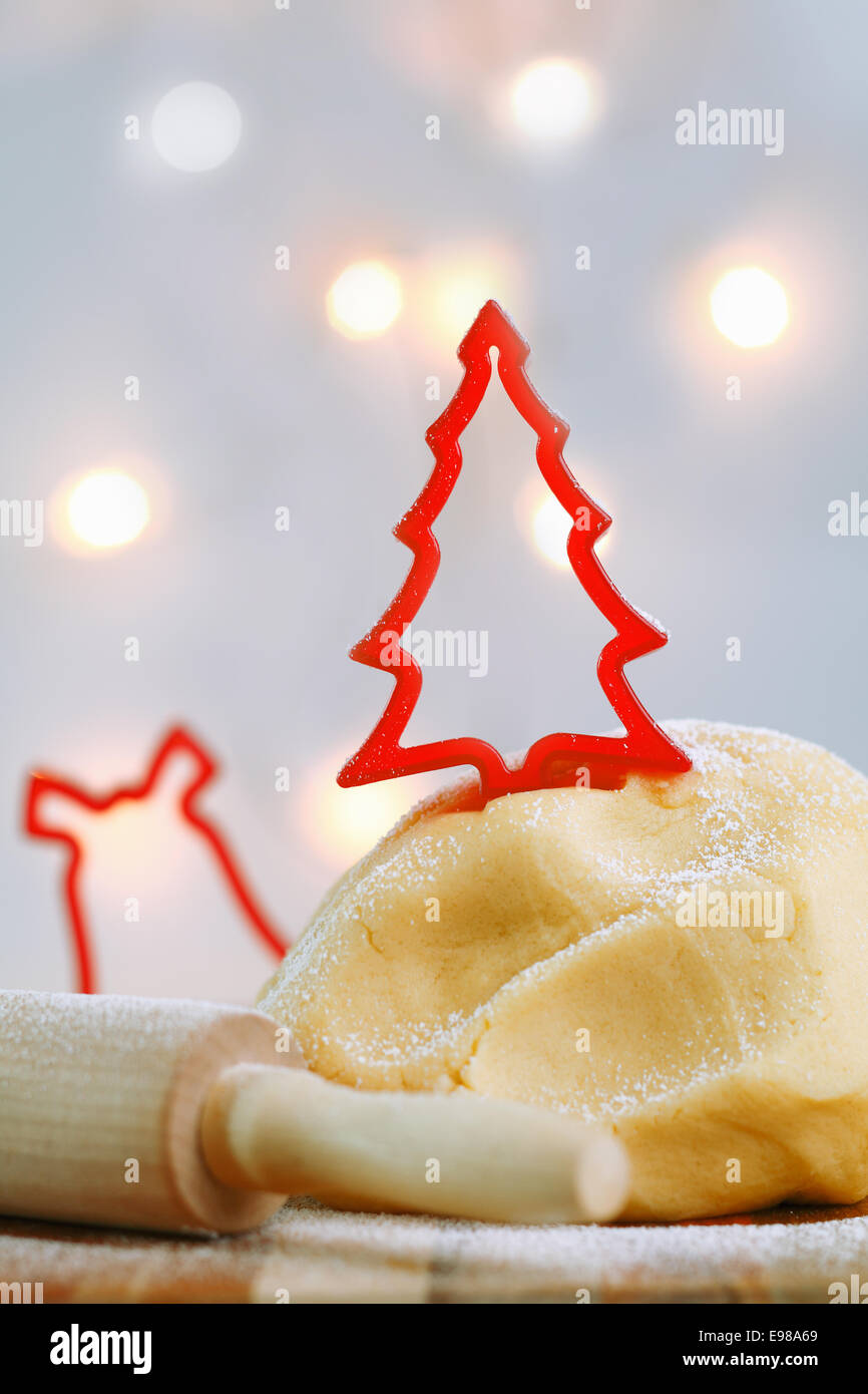 Una cookie cutter rojo en la forma de un árbol de Navidad tops un montículo de pastelería recién hechas mientras se prepara la masa galletas de Navidad Foto de stock