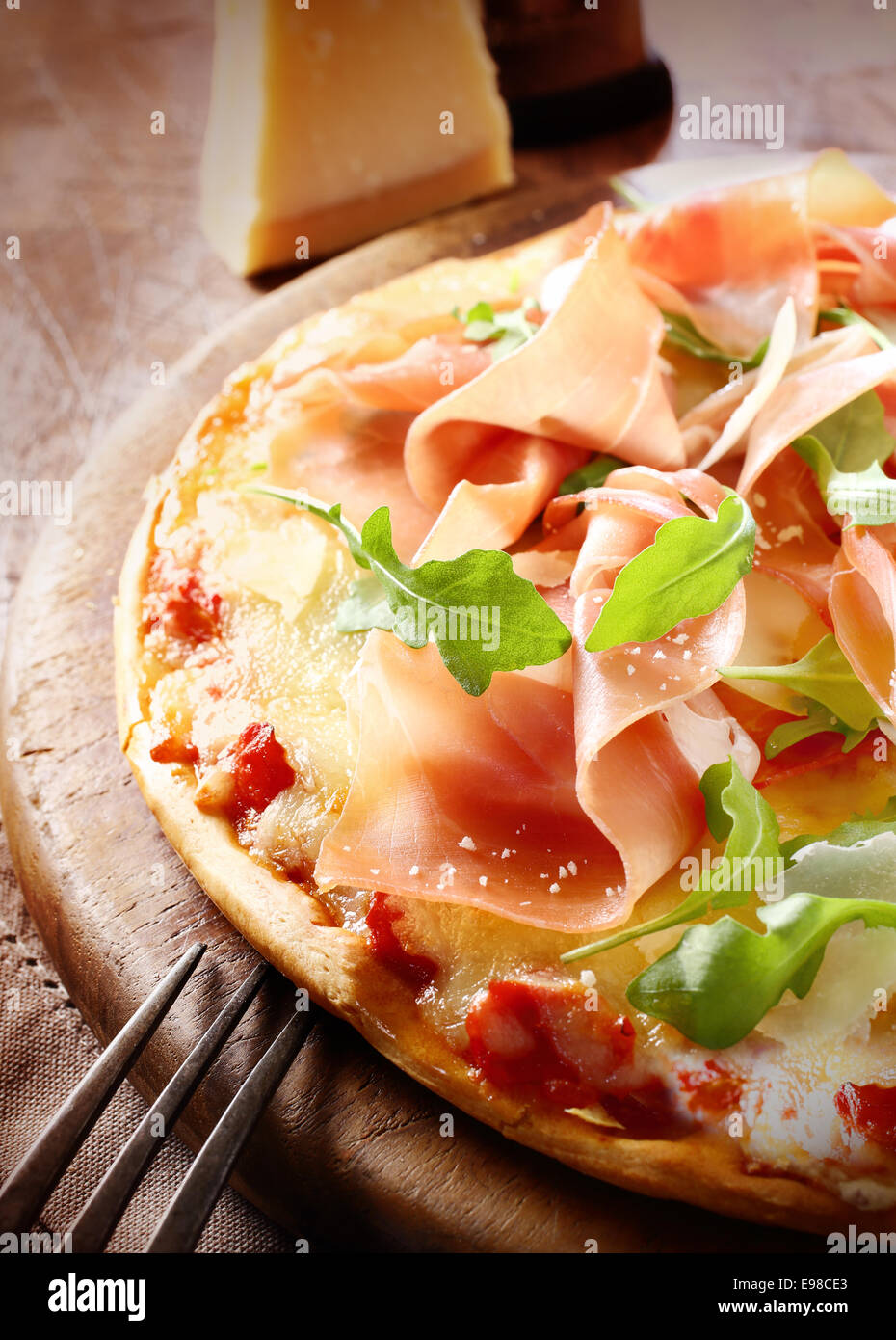 Delicioso jamón italiano recién horneados y rúcula pizza con una rociada de  queso parmesano servido entero en una placa de madera redondo. Más pizza en  mi puerto Fotografía de stock - Alamy