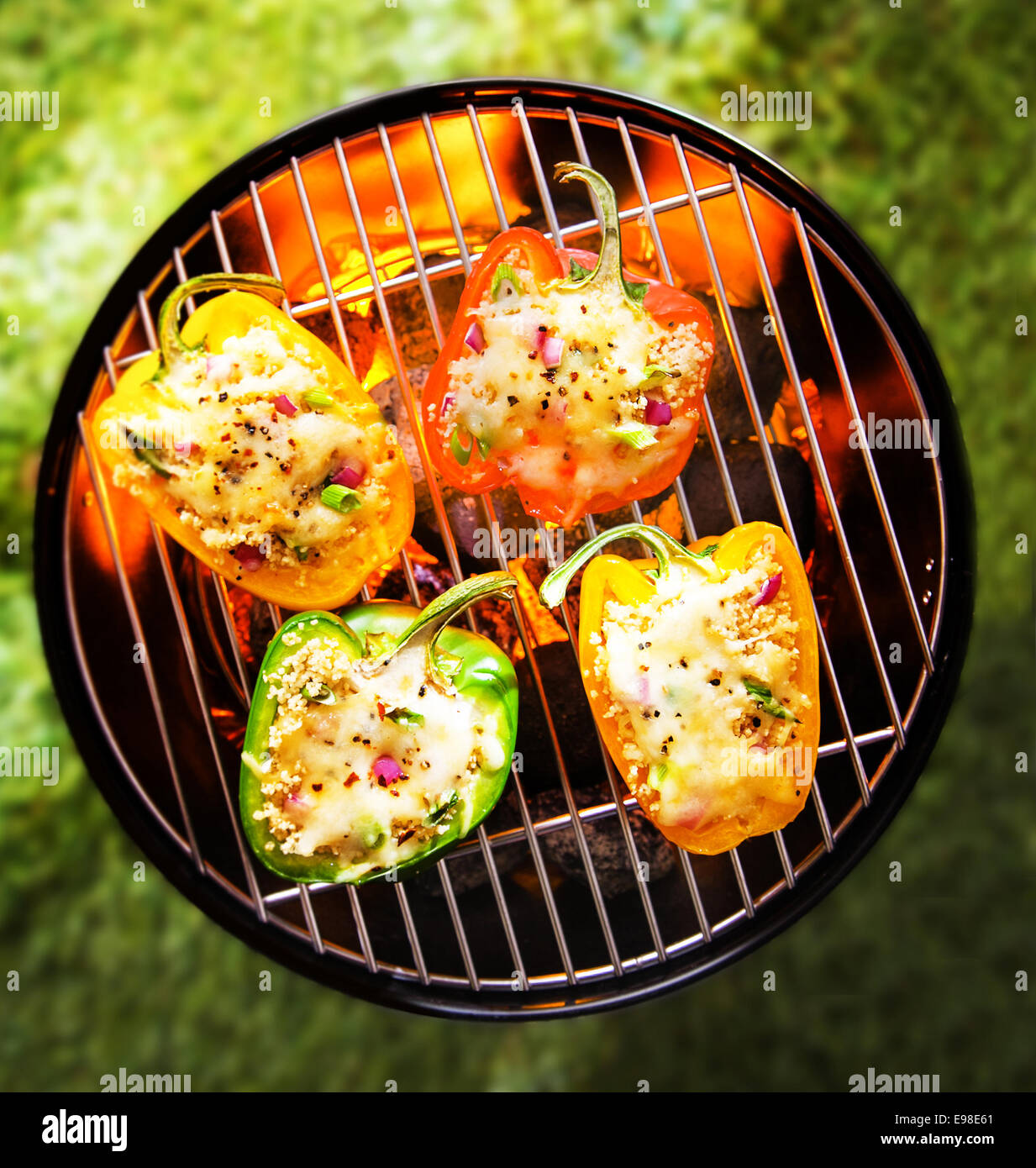 Vista desde arriba de color rojo, verde y amarillo veggy rellenos salados asar pimientos en una barbacoa con brillantes brasas Foto de stock