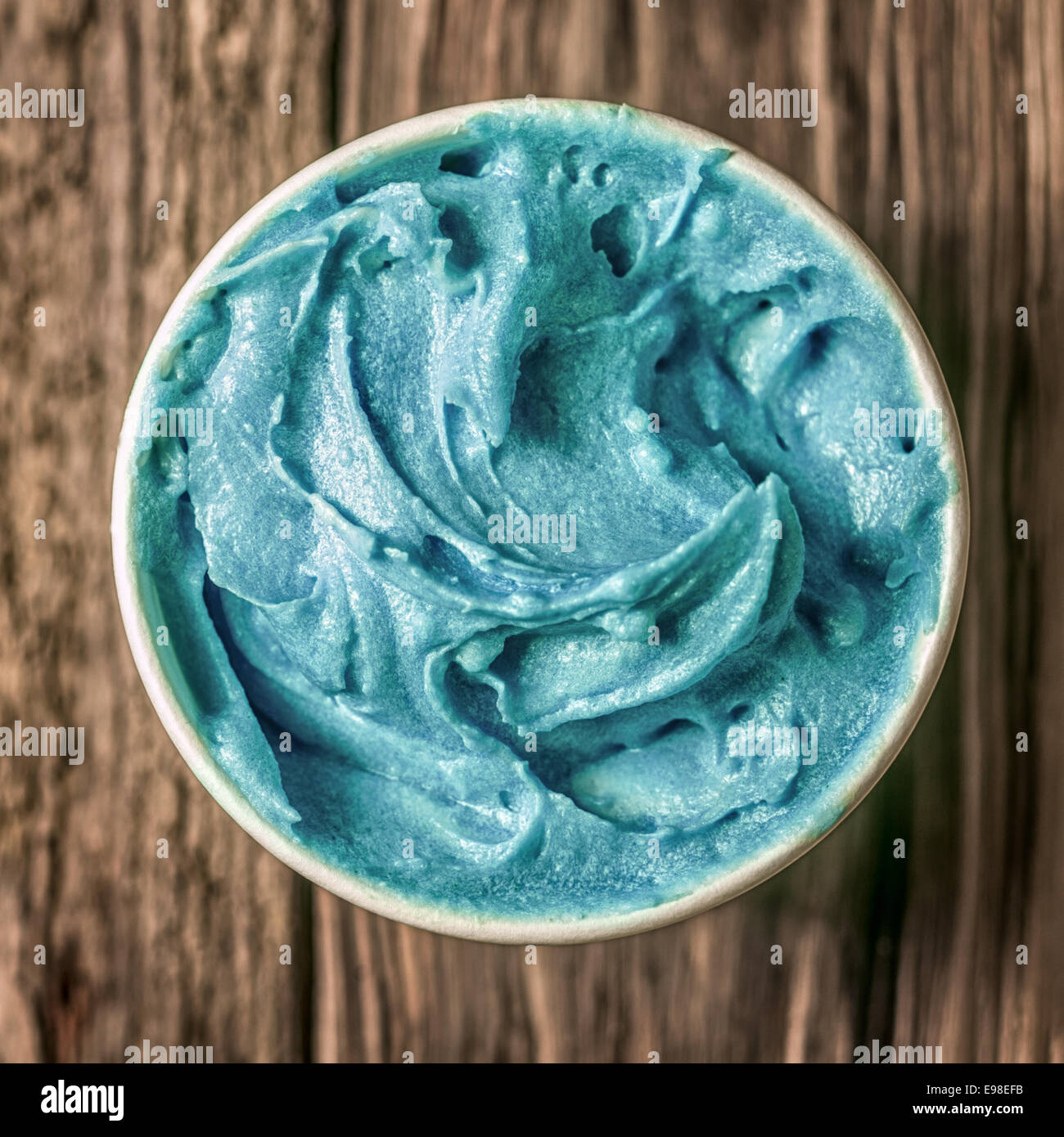 Azul turquesa refrescantes helados en una bañera para llevar parado sobre una antigua mesa de madera con textura, vista aérea en formato cuadrado Foto de stock