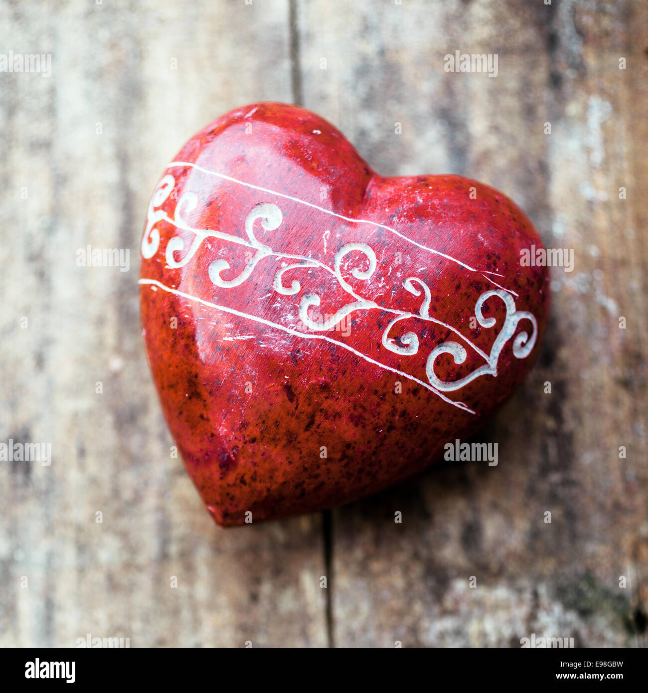 Romántico corazón rojo con un patrón de grabado a mano sobre un fondo de madera rústica, vista desde arriba simbólica de amor, novios, aniversario y el Día de San Valentín Foto de stock
