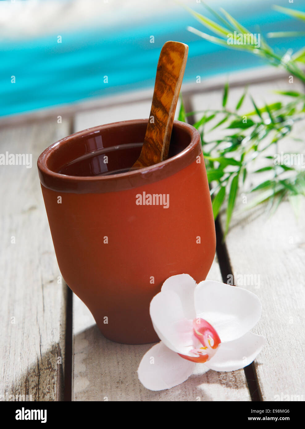 Vaso de Leche de coco, la bebida con una cuchara de madera y una orquídea. En frente del mar. Conceptos para la bebida. Foto de stock