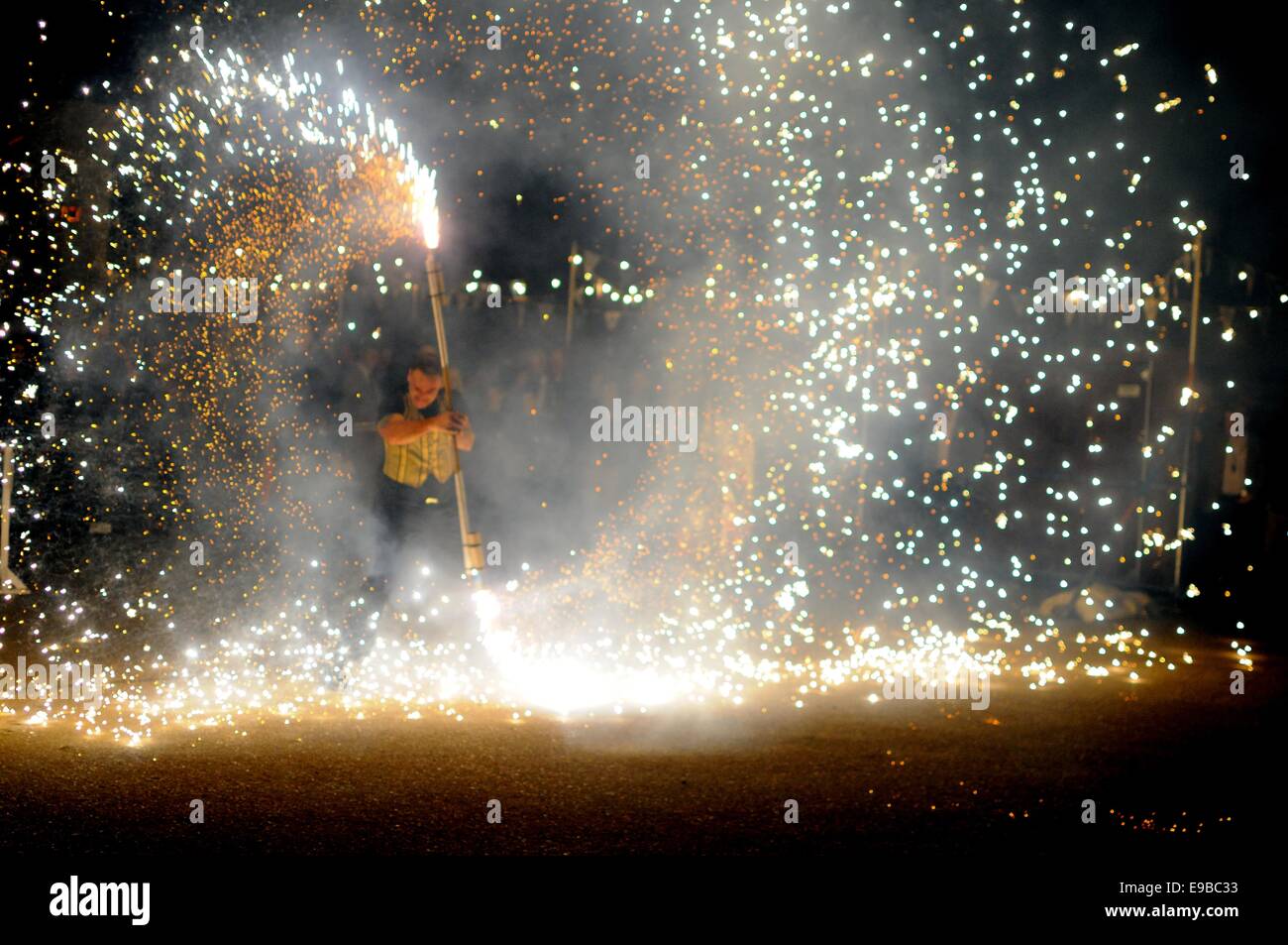 Un recinto ferial performer gira una porra de fuegos artificiales Foto de stock