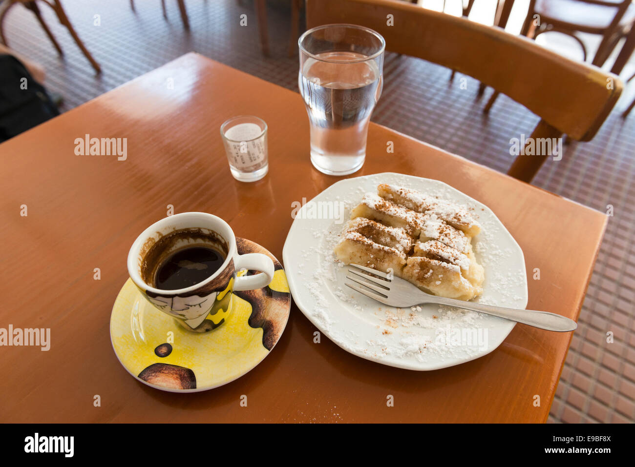 Stilllife de pastelería (Baklava) en el plato, taza de café griego, un vaso de agua y el proyecto de ley en un vaso, la isla de Kos, Grecia Foto de stock