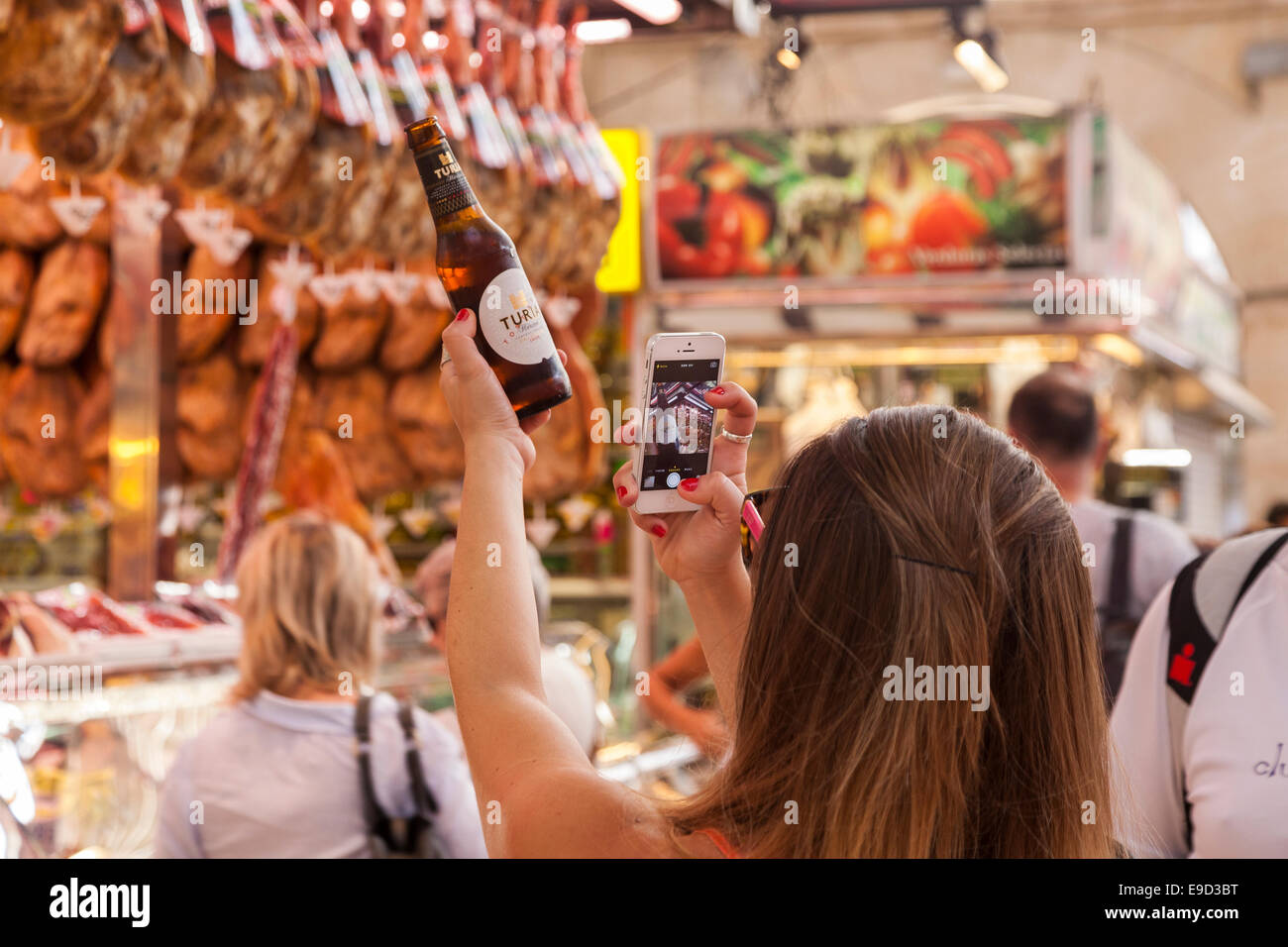 Mujer fotografiando botella de cerveza con su iphone en el mercado central, Valencia, España. Cerveza llamado después de que el río Turia Foto de stock