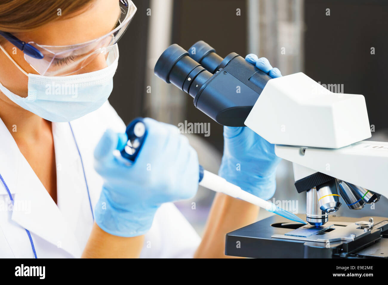 Bella mujer en un laboratorio trabajando con un microscopio. Foto de stock