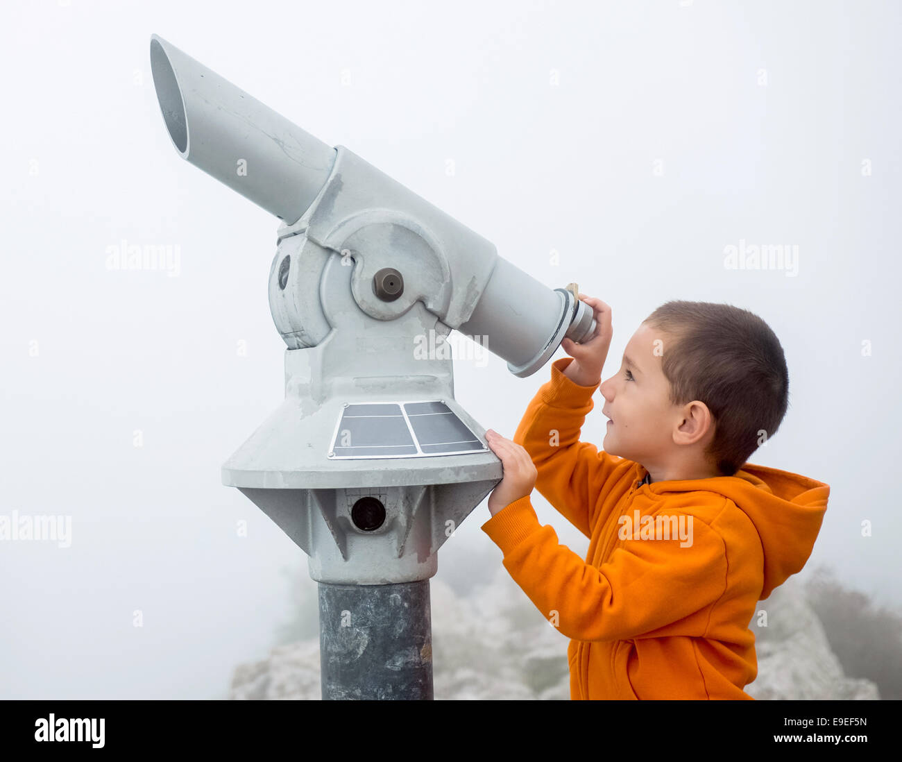 Niño mirando hacia el cielo a través de un catalejo Foto de stock