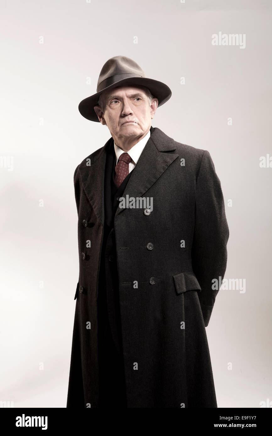 Traditional Continuous Sherlock Holmes Viejo hombre característico sombrero trilby y abrigo largo mirando como un  detective / Policía / gangster en traje blanco disparó contra Fotografía de  stock - Alamy