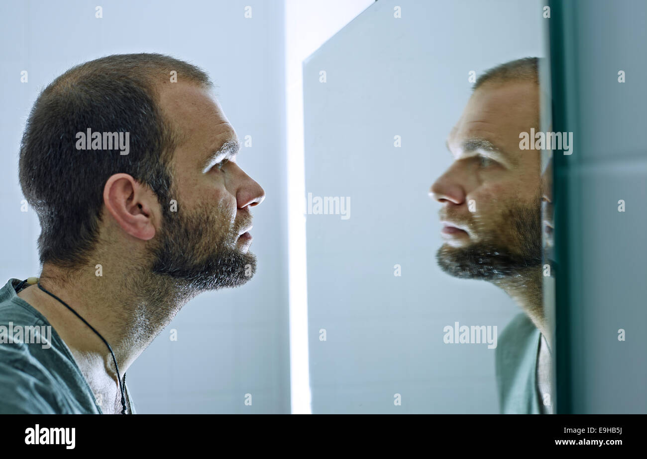 El hombre con barba mirando a un espejo Foto de stock
