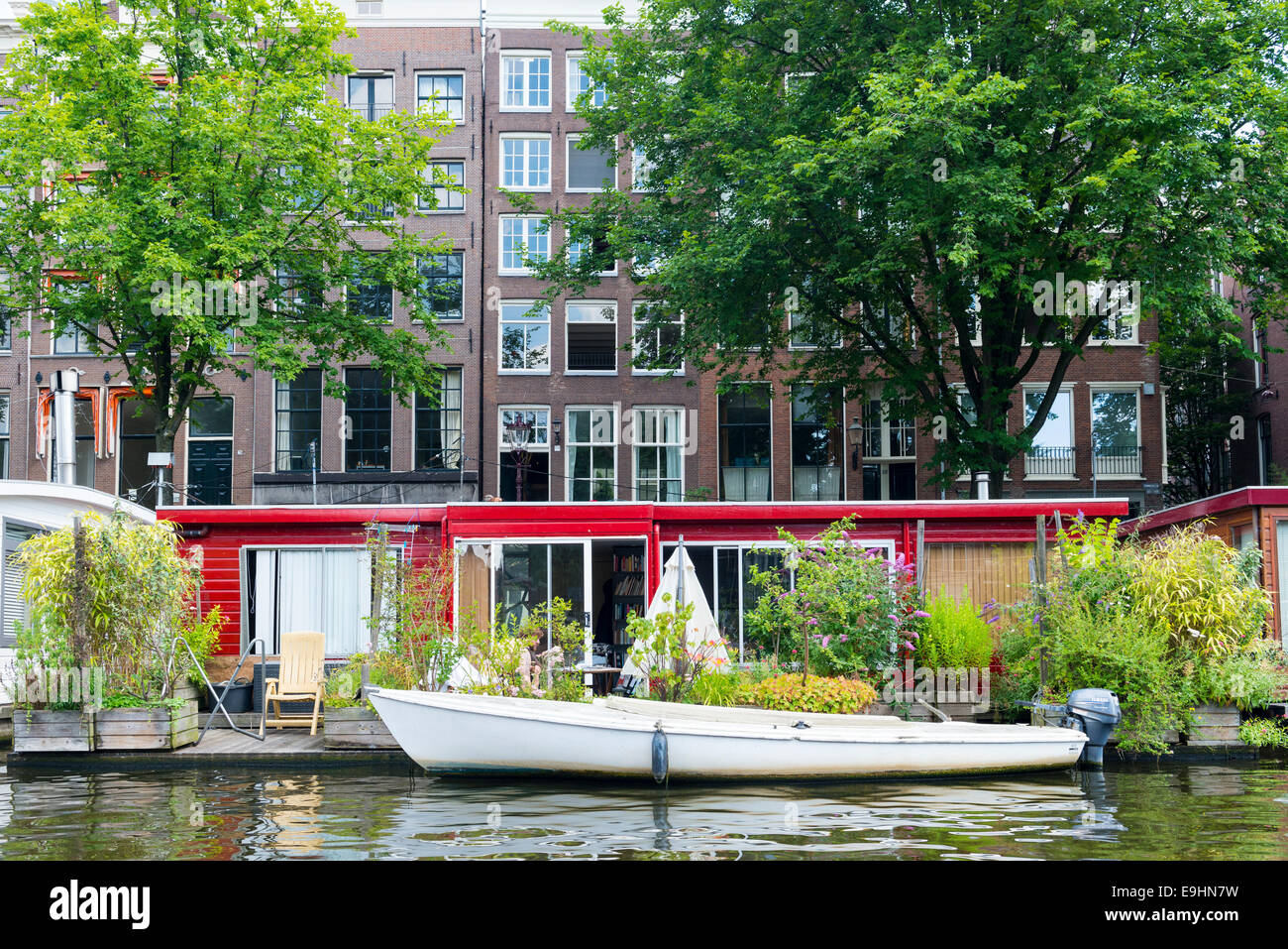 Casa flotante en el banco de un canal con un patio y plantas, Amsterdam, Países Bajos Foto de stock