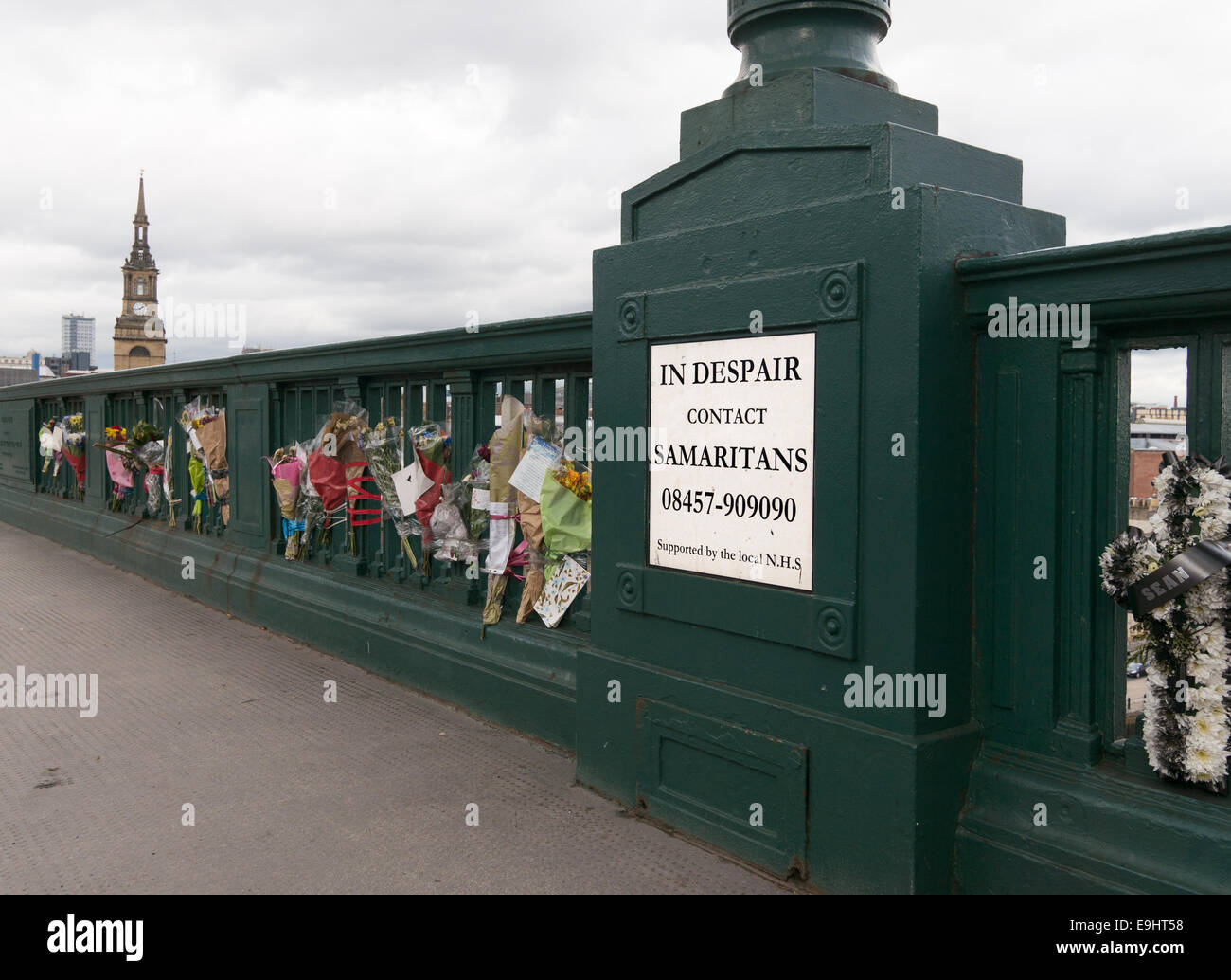 Samaritanos cartel con número de teléfono de emergencia en el Tyne Bridge con homenajes florales, al noreste de Inglaterra Foto de stock