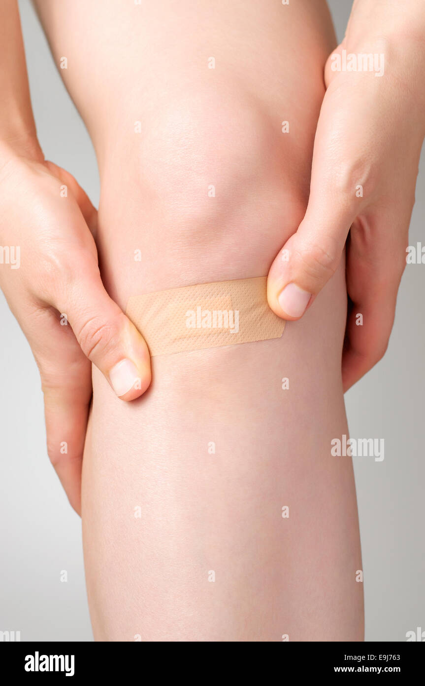 Mujer poner una venda adhesiva en la pierna Foto de stock
