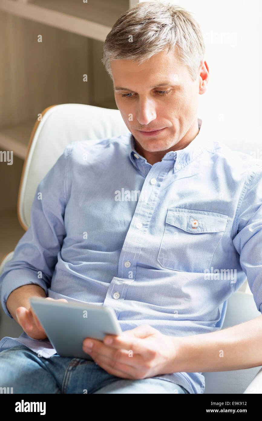 Hombre de mediana edad con tableta digital en casa Foto de stock