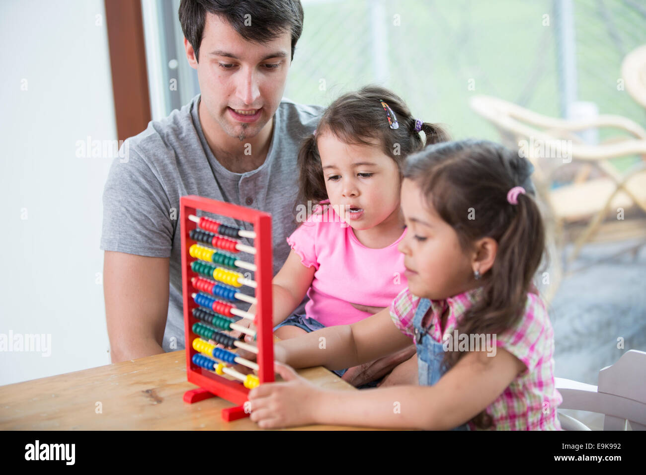 Padre e hijas jugando con abacus en casa Foto de stock