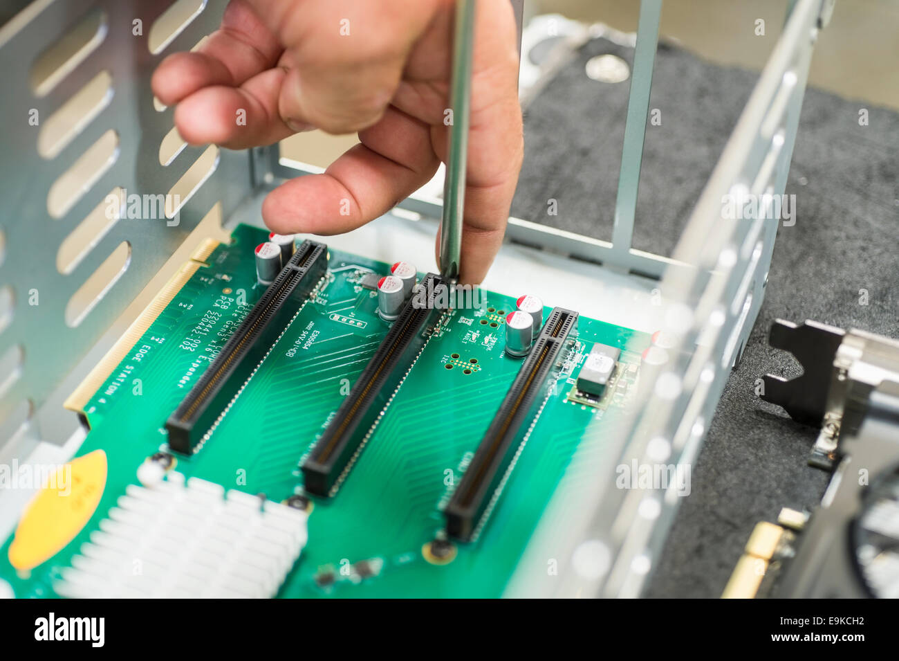 Imagen recortada de técnico masculino Reparación de ranuras PCI en el equipo de fábrica Foto de stock
