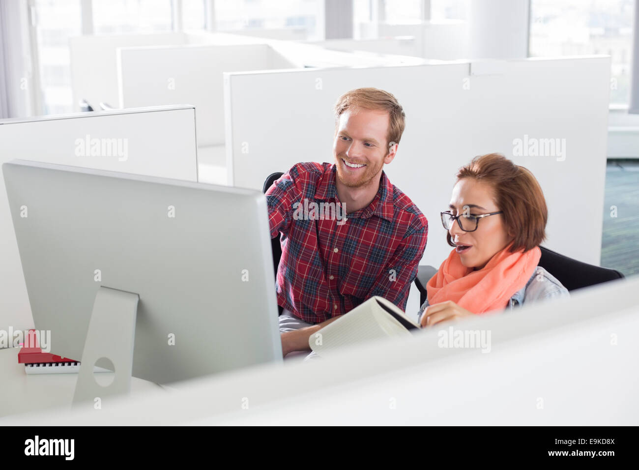 Empresario y empresaria utilizando el ordenador en la oficina creativa Foto de stock