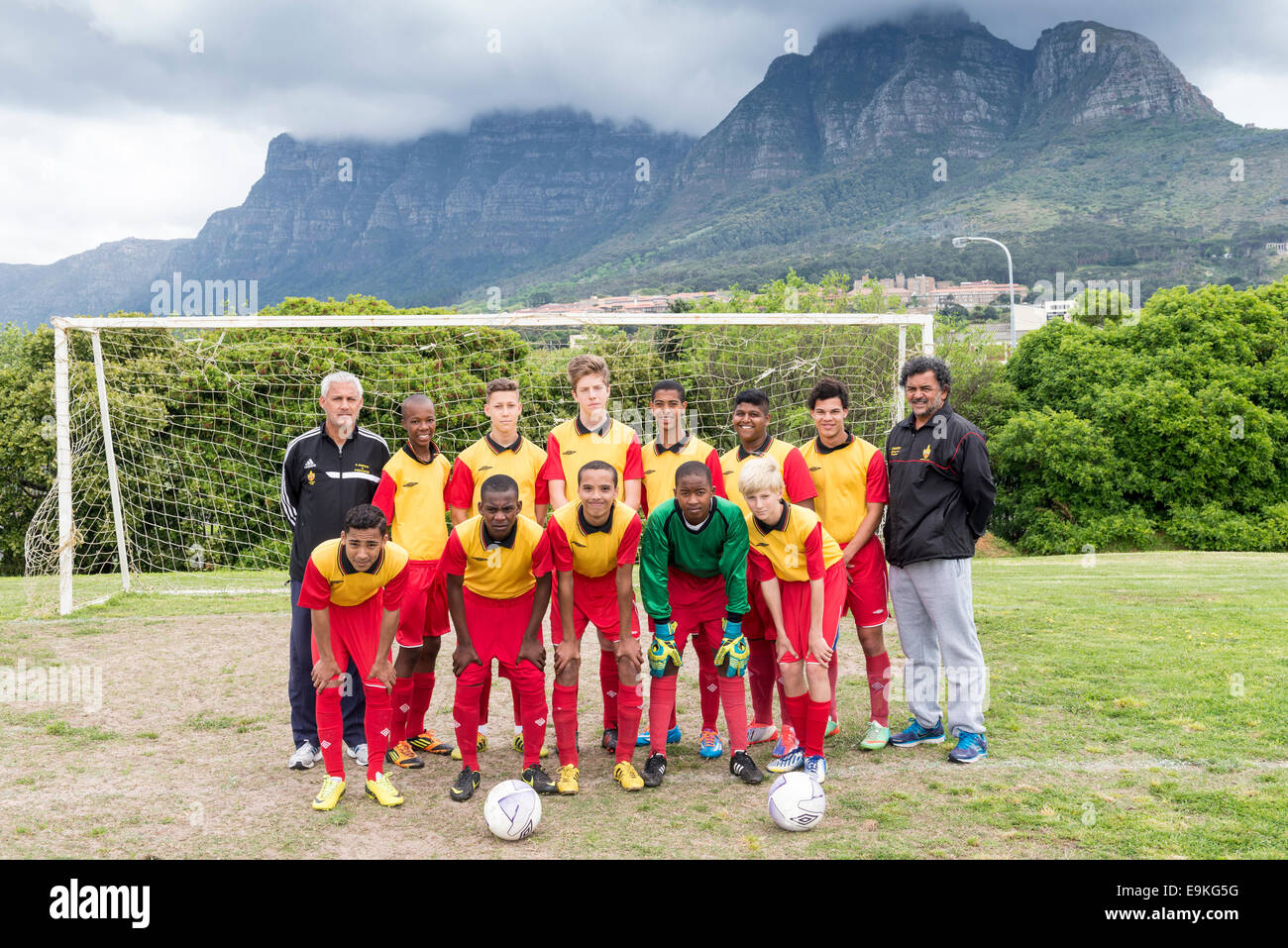 Equipo de fútbol juvenil (U15) con entrenadores posa delante de un objetivo de Ciudad del Cabo, Sudáfrica Foto de stock