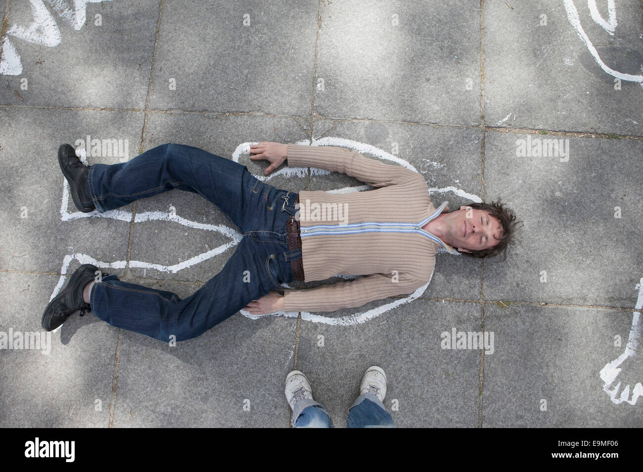 Un alto ángulo de vista de esquema de tiza alrededor del hombre tumbado en la calle Foto de stock