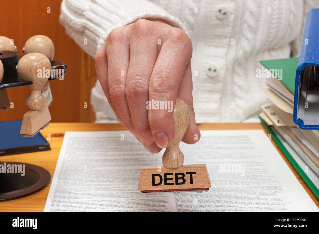 Un sello con la inscripción deuda es sostenido en la mano Foto de stock