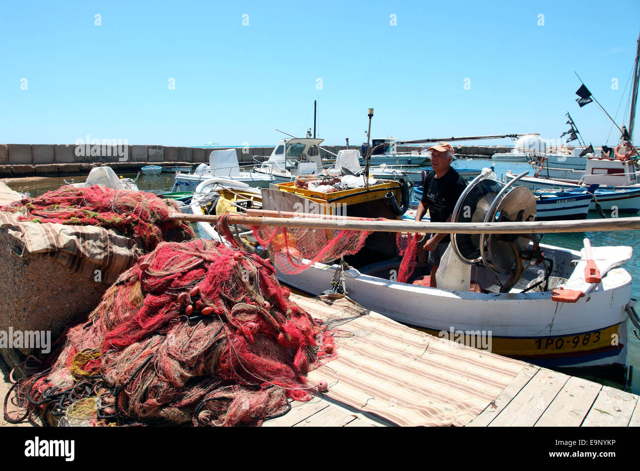Un pescador a bordo de su barco en marina de Ragusa, en el sudeste de Sicilia. Foto de stock