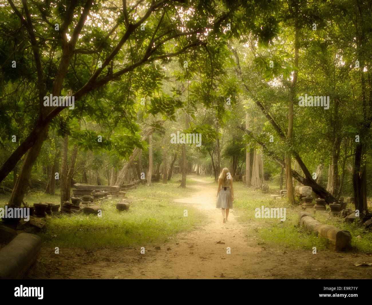 Mujer joven caminando sobre un misterioso camino en un bosque encantado. Foto de stock