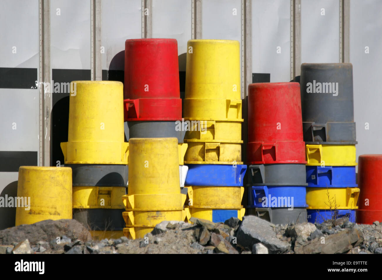 Colorido plástico viejo latas apiladas en sitio de construcción. Foto de stock