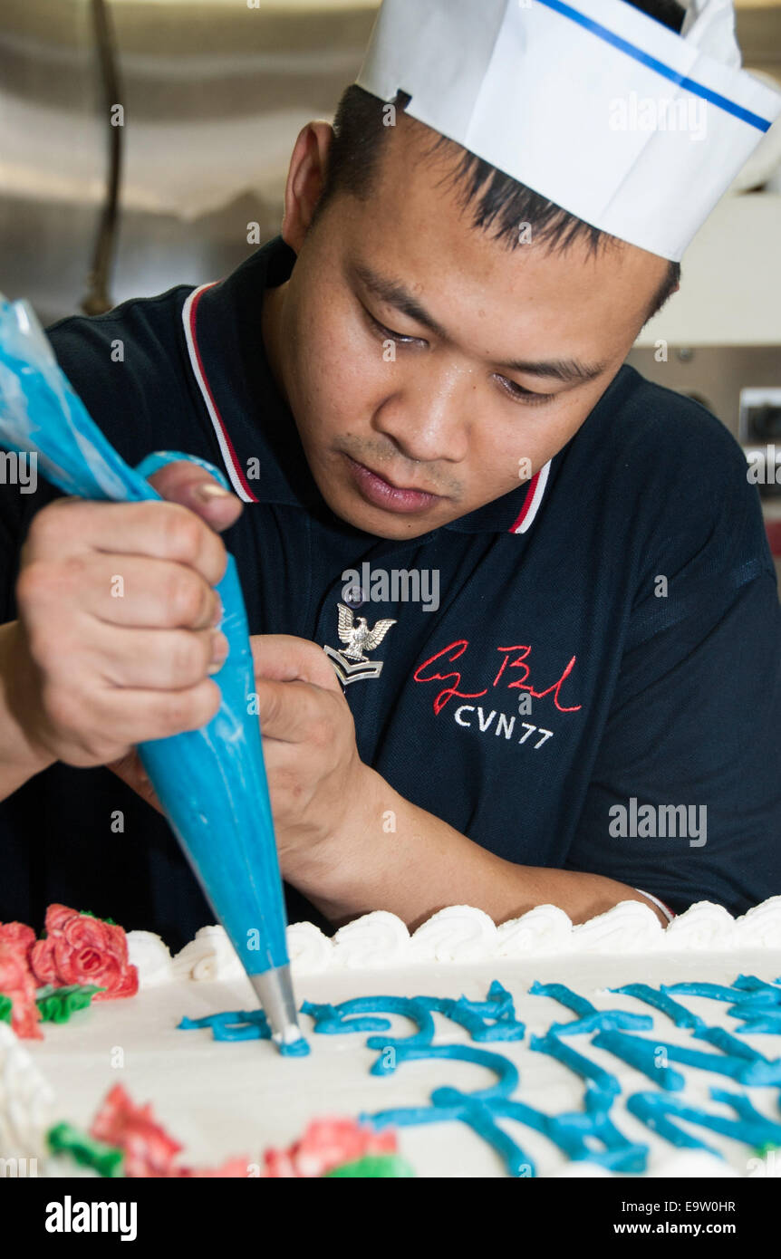 Marina de los EE.UU. 2ª clase especialista culinario Edgar Baldov decora una tarta a bordo del portaaviones USS George H.W. Bush (CVN 77) Foto de stock